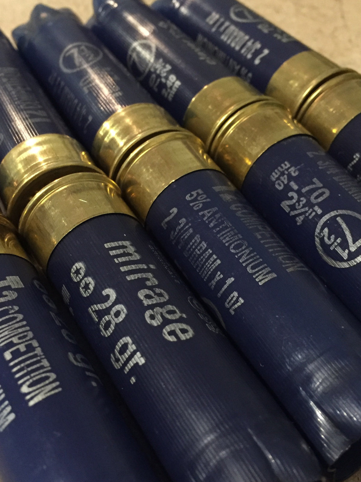 Close-up angled view of navy blue shotgun shell hulls and gold brass bases showing mirage and T2 Competition text