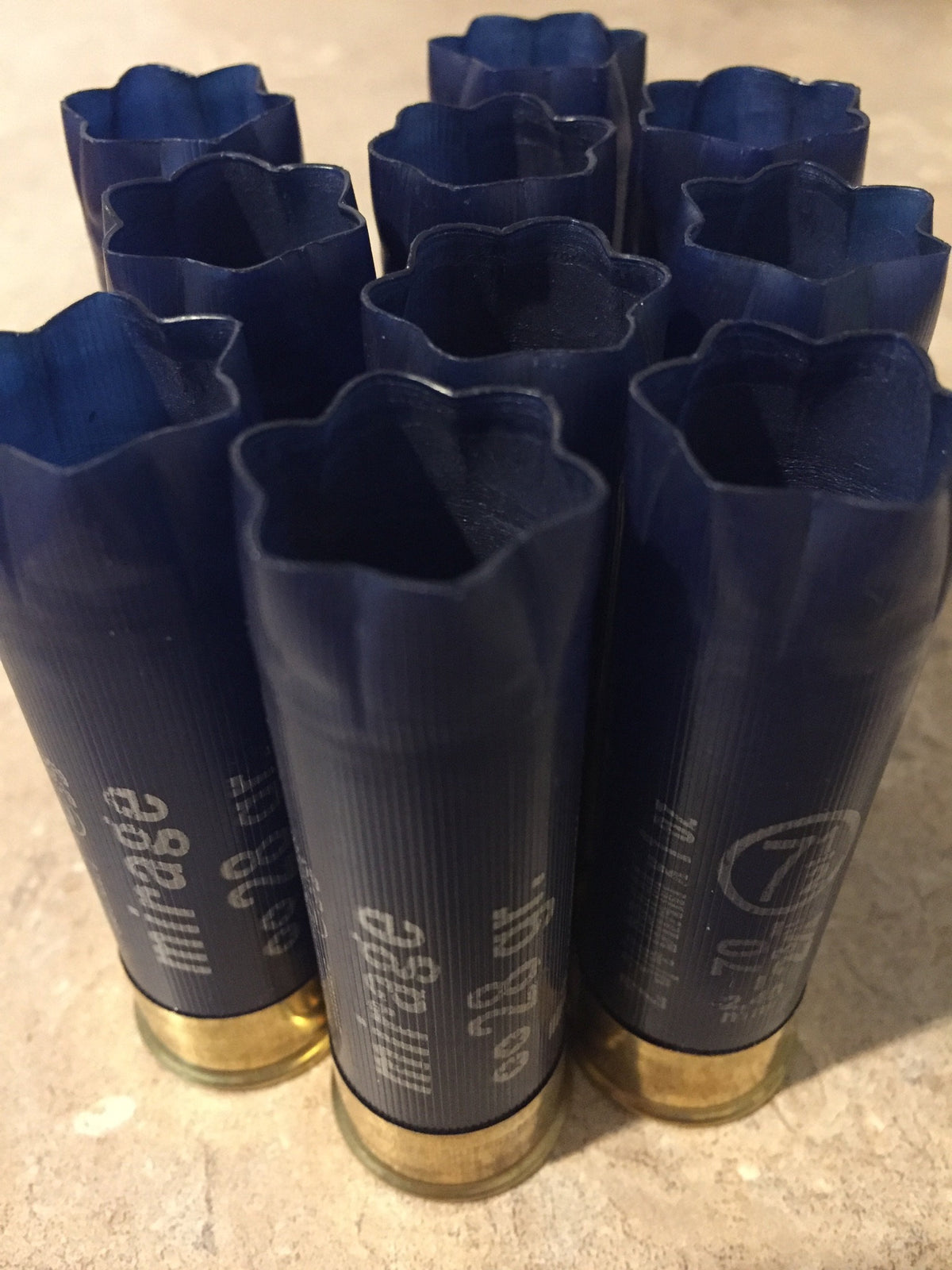 10 navy blue shotgun shells viewed from open crimped end, star-shaped crimp pattern visible on each hull