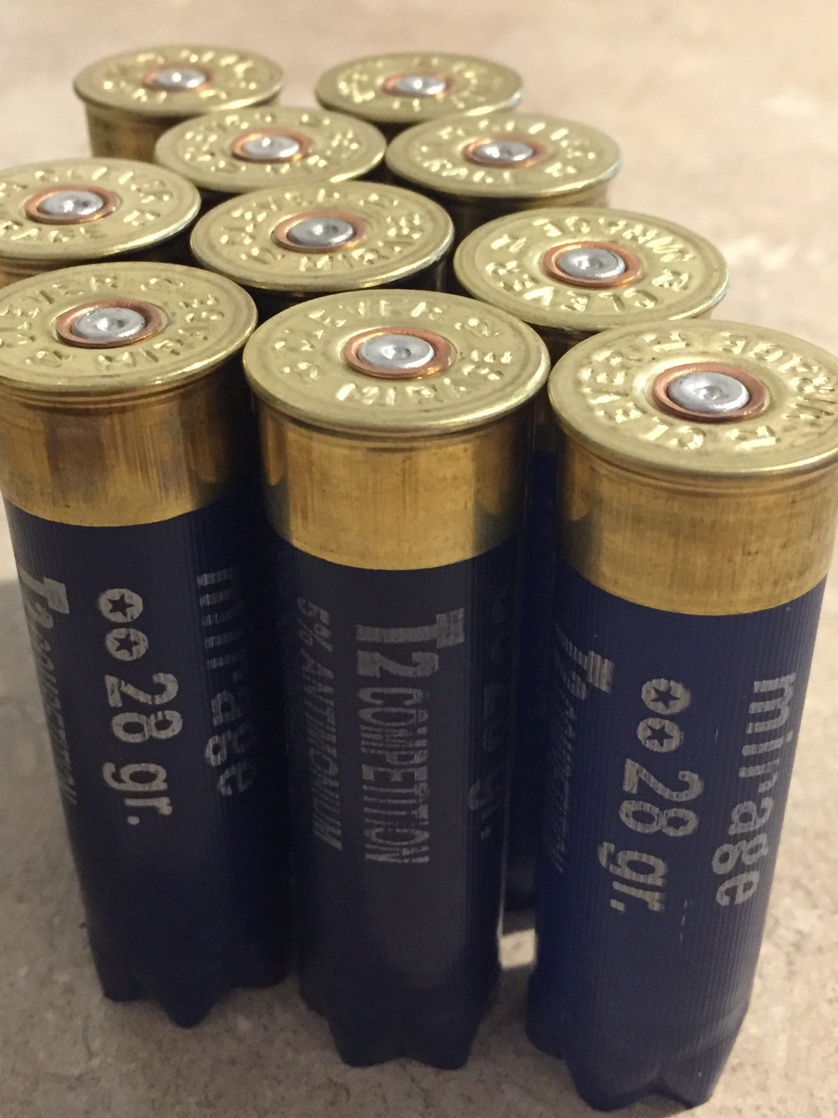 10 navy blue shotgun shell brass bases viewed from above in cluster, Clever Mirage 12 gauge headstamps visible