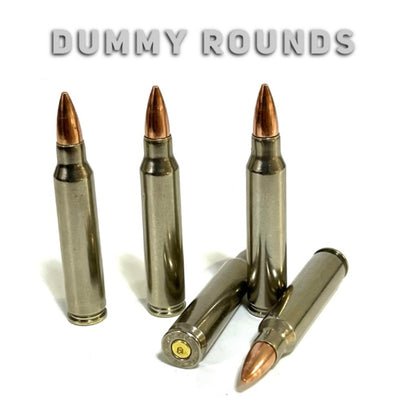 Five nickel-plated .223 dummy rifle cartridges with copper bullet tips on white under overlay text reading DUMMY ROUNDS.