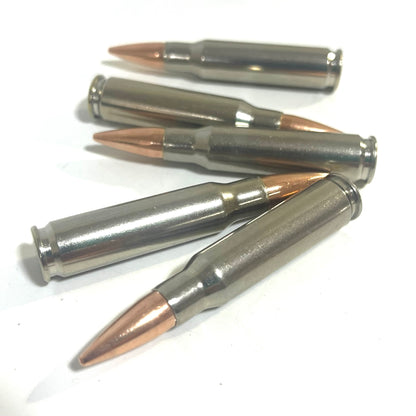 Five nickel-plated .308/7.62x51 dummy cartridges scattered and crossed on a white surface