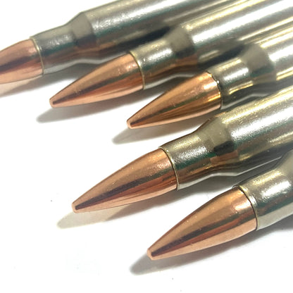 Close-up of five nickel-plated .308/7.62x51 dummy cartridges angled with copper bullet tips facing the camera