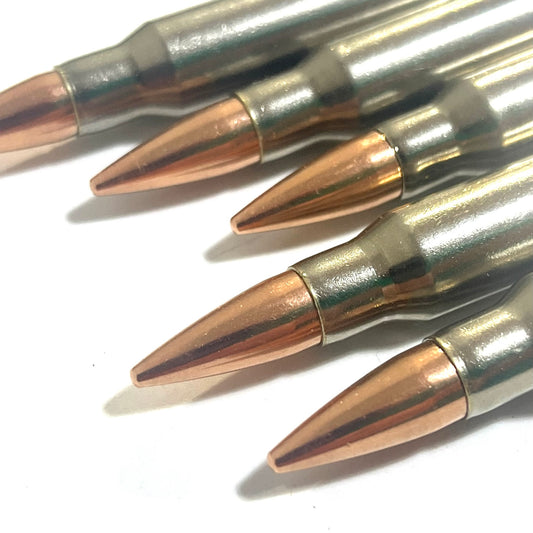 Close-up of five nickel-plated .308/7.62x51 dummy cartridges angled with copper bullet tips facing the camera