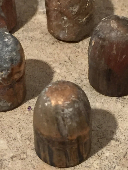 Close-up of 4 tarnished spent bullets standing upright on a stone surface