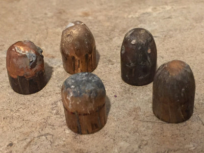 5 tarnished spent bullets standing upright in a cluster on a stone surface