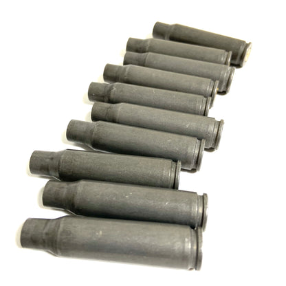 Single gray steel 308 casing lying next to a wooden ruler showing its length