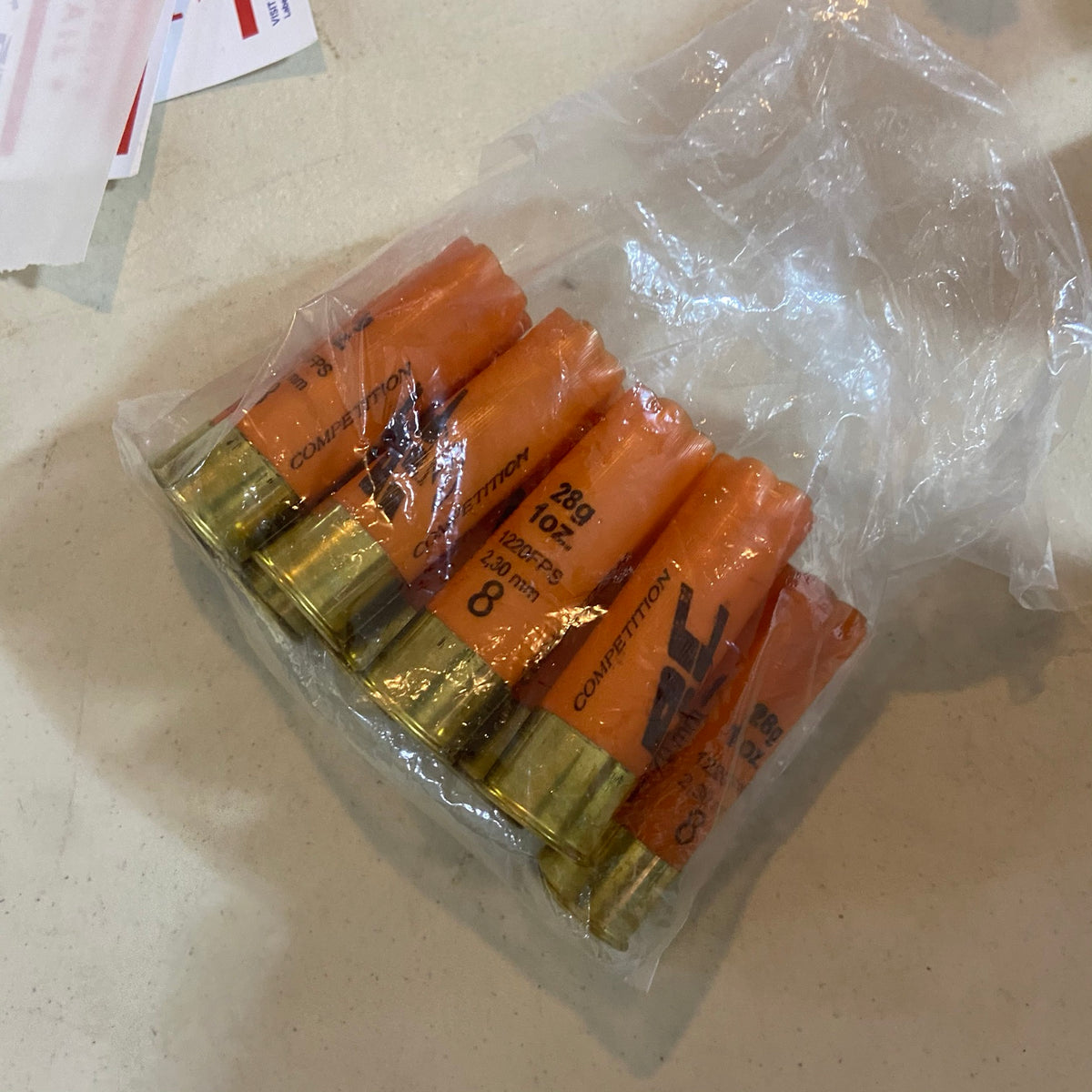 Empty orange Competition shotgun shells with gold bases in a clear plastic bag