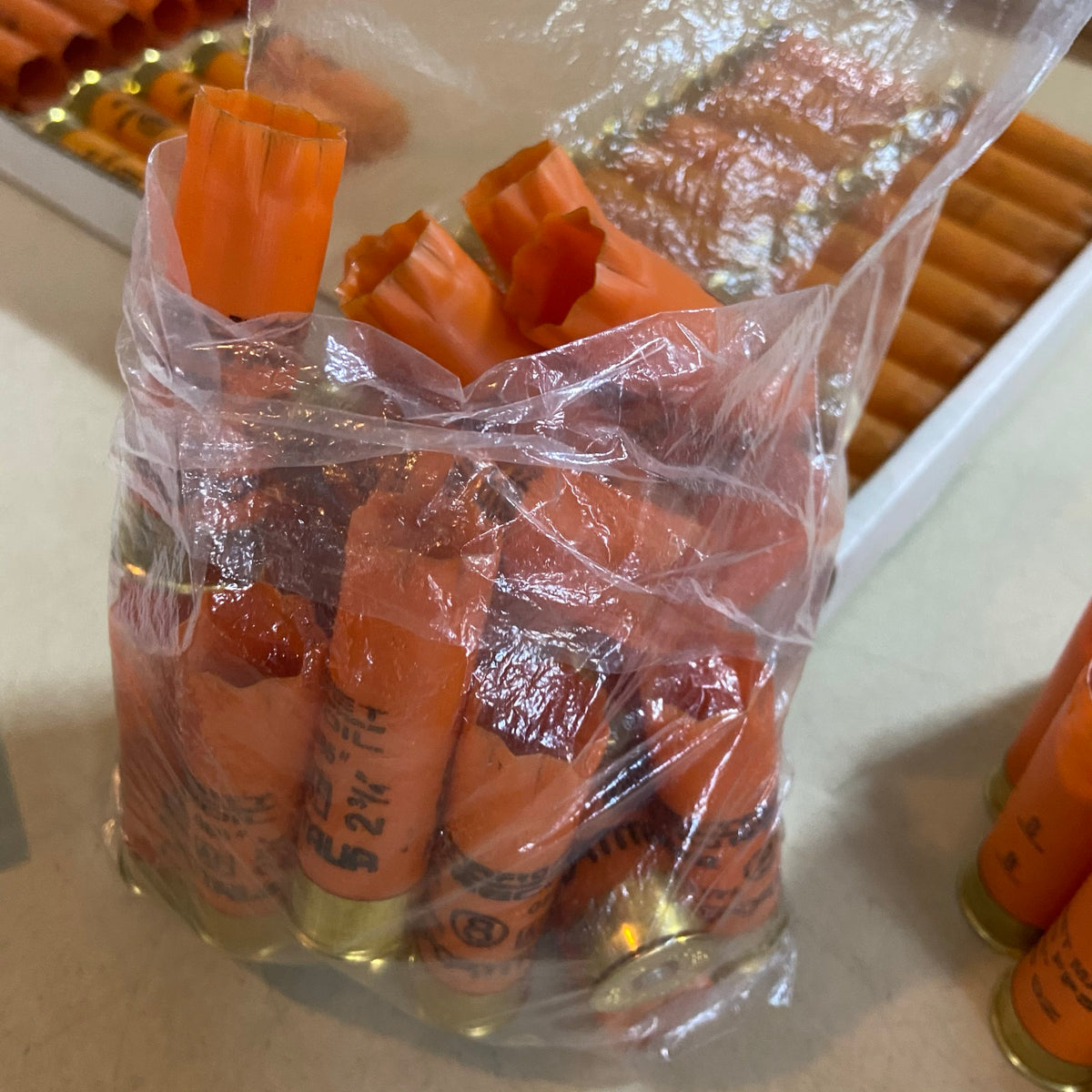 Empty orange shotgun shells with gold bases in a clear plastic bag