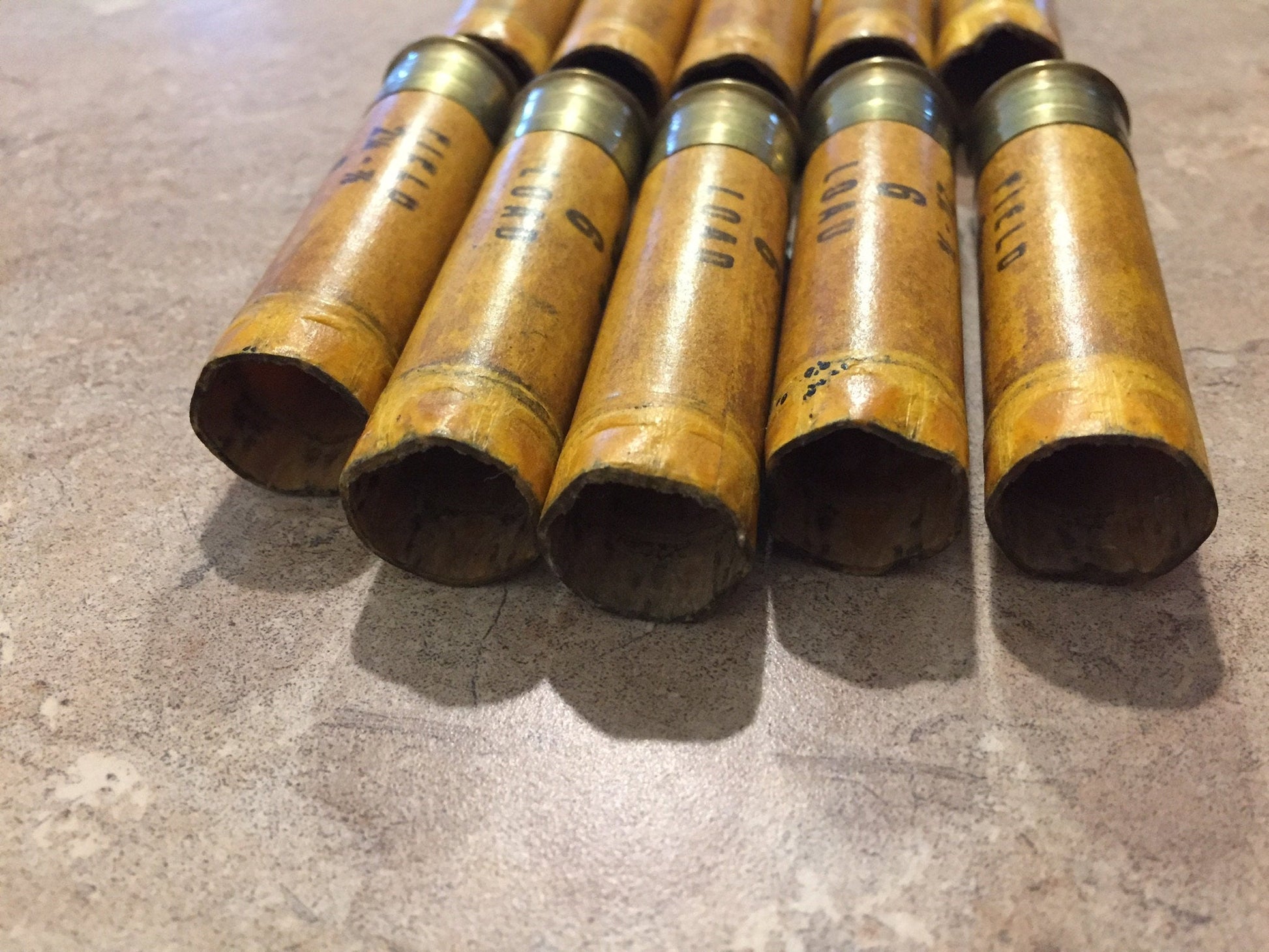 Five vintage tan paper 20 gauge shotgun shell hulls lying with open ends showing “Field” and “Load” printing