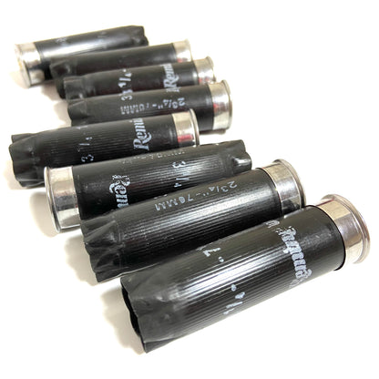 Large pile of once fired black Remington 12 gauge empty shotgun hulls with silver bases and printed text.