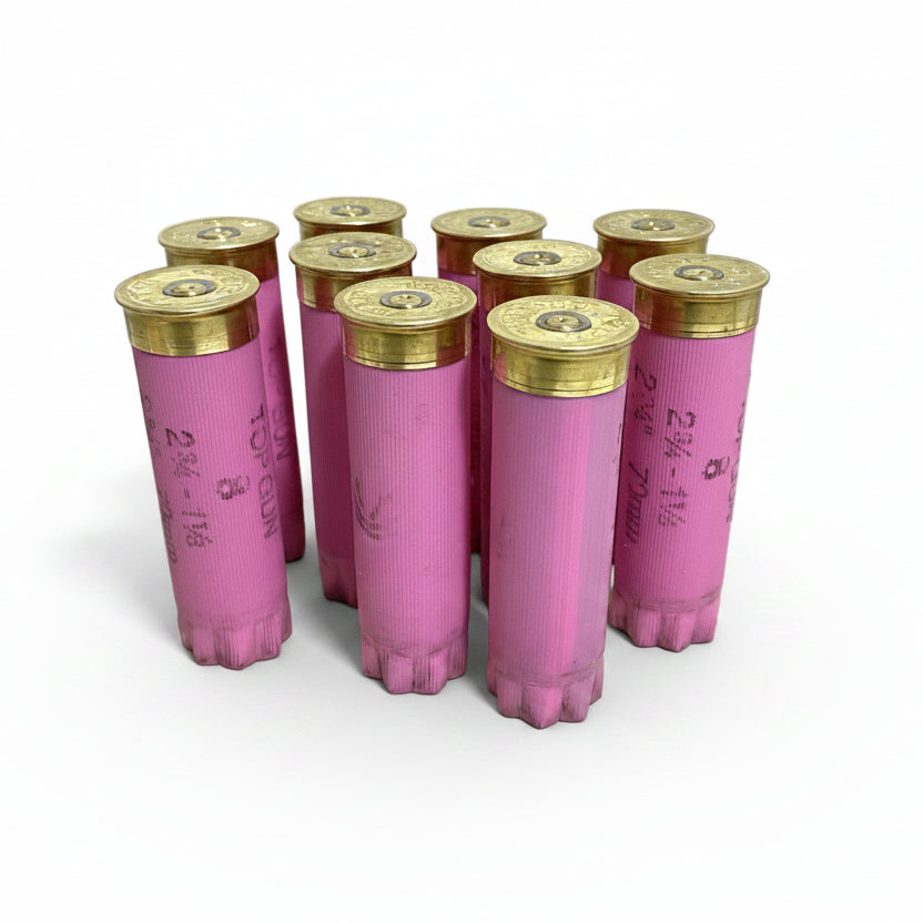 Nine pink Federal Top Gun empty hulls standing upright with brass primer ends facing up, white background.