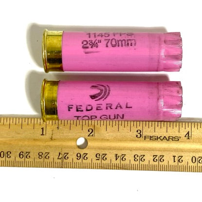 Two pink Federal Top Gun casings beside a ruler, showing 2 3/4 inch length and brass bases up close.