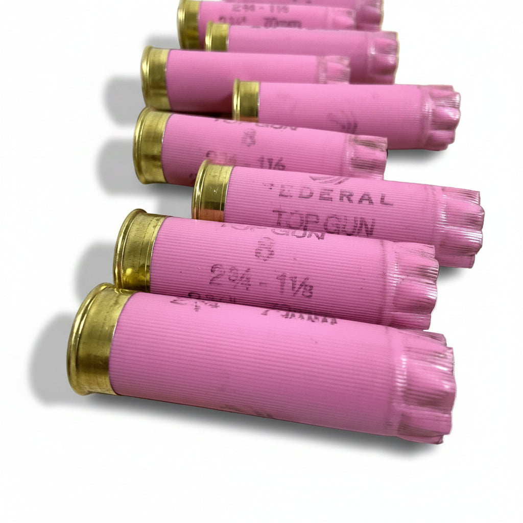 Close-up of pink Federal Top Gun empty shells lined up diagonally, showing brass rims and stamped markings white background.