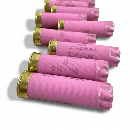 Close-up of pink Federal Top Gun empty shells lined up diagonally, showing brass rims and stamped markings white background.
