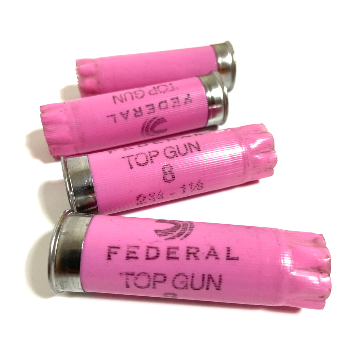 Four pink Federal Top Gun 12 gauge empty shotgun shells with silver bases on a white background