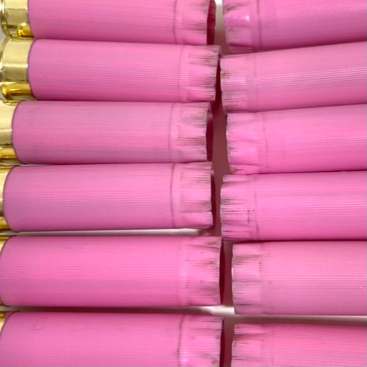 Extreme close-up of once-fired pink shotgun hull crimped tops, packed tightly in two rows with a bit of brass visible.