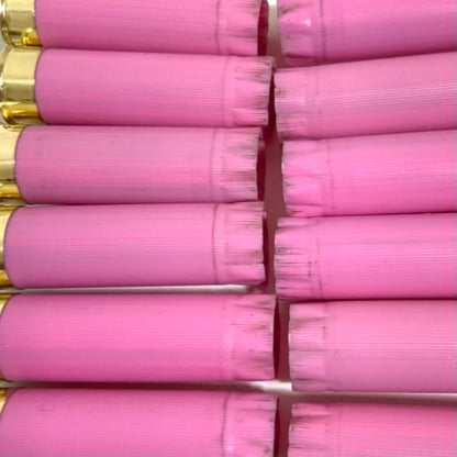 Extreme close-up of once-fired pink shotgun hull crimped tops, packed tightly in two rows with a bit of brass visible.