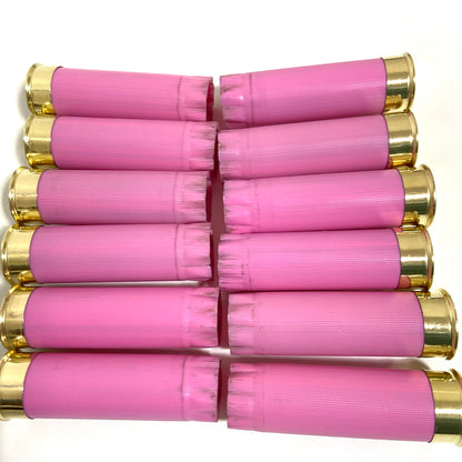 Twelve spent pink shotshells arranged neatly in two rows, alternating brass ends left and right.