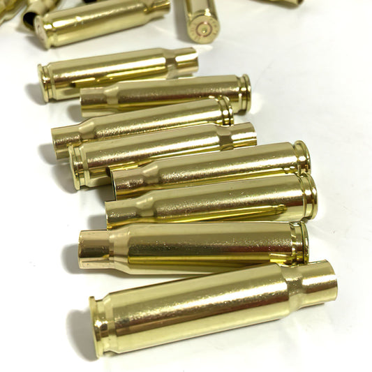 Eight polished gold 308 WIN brass shells stacked horizontally on a white background, displaying one base headstamp.