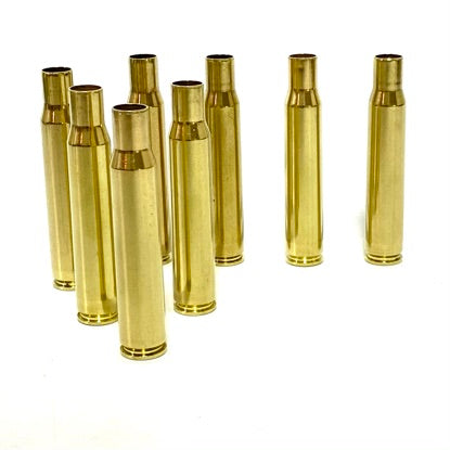 Seven polished brass casings standing upright in a clustered group against a clean white background.
