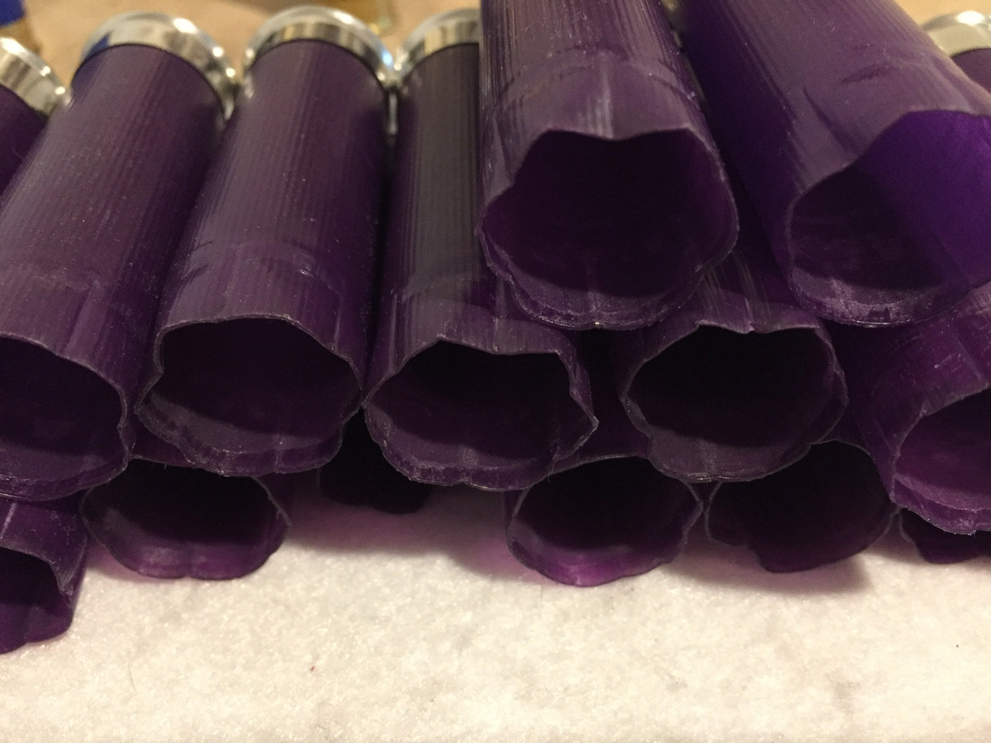 Row of purple shotgun shell hulls viewed from open crimped end, star-shaped crimp openings, silver bases behind