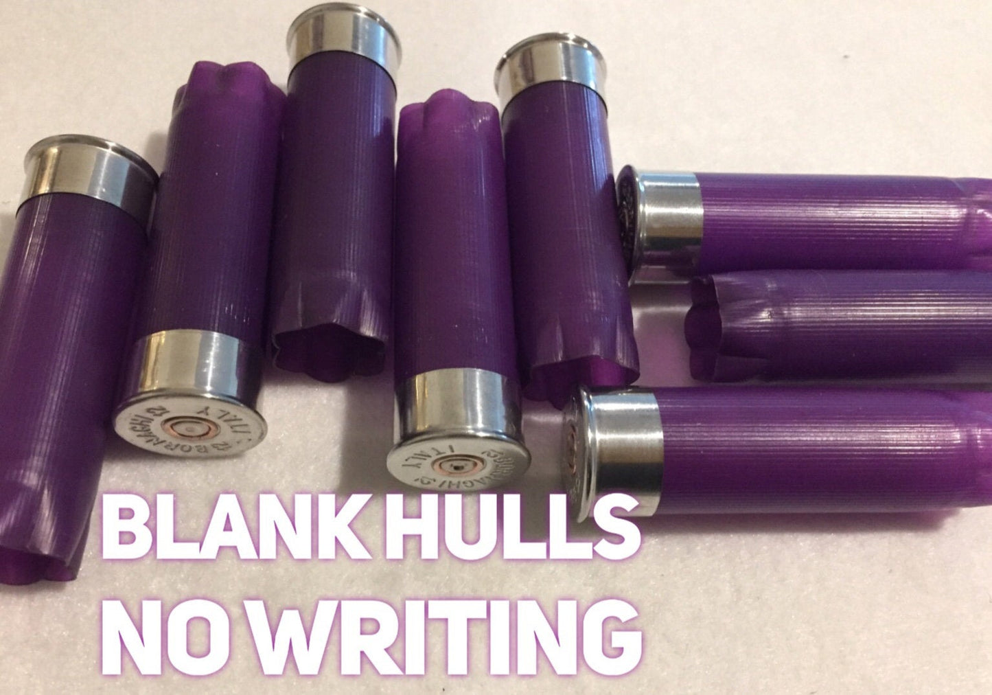 Purple empty 12-gauge shotgun shell hulls with text reading “Blank hulls, no writing”