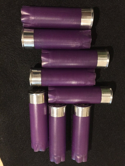 Purple empty 12-gauge shotgun shell hulls arranged on a black background