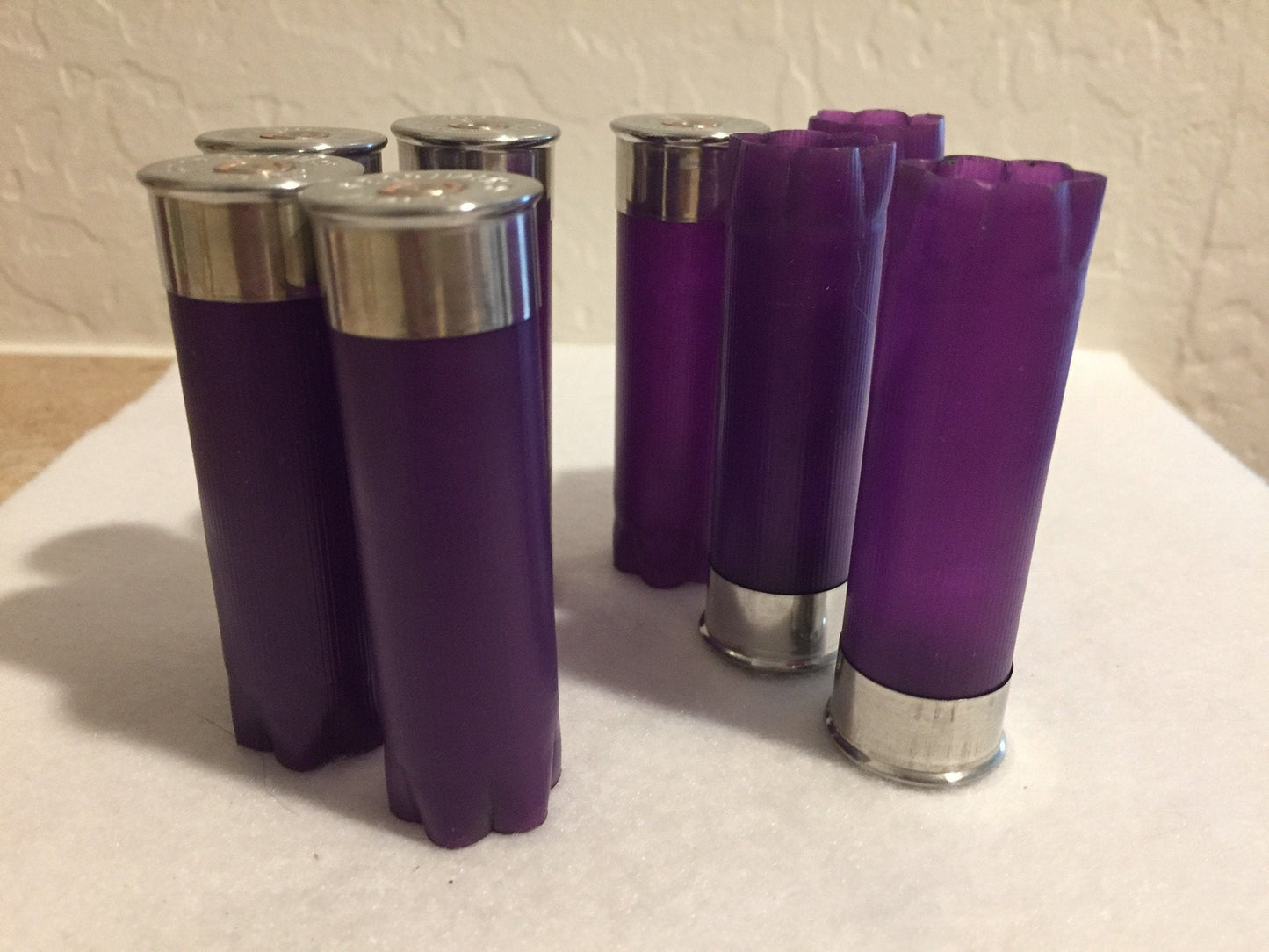 Purple empty 12-gauge shotgun shell hulls grouped upright on a light background