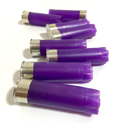 Purple empty 12-gauge shotgun shell hulls scattered on a white background