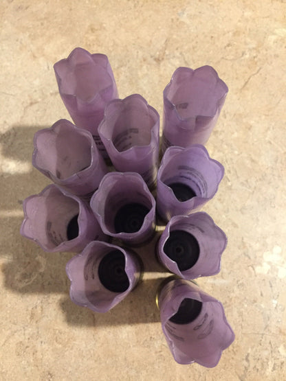 9 purple Fiocchi shotgun shells with crimped star-fold tops, viewed from above showing open mouths