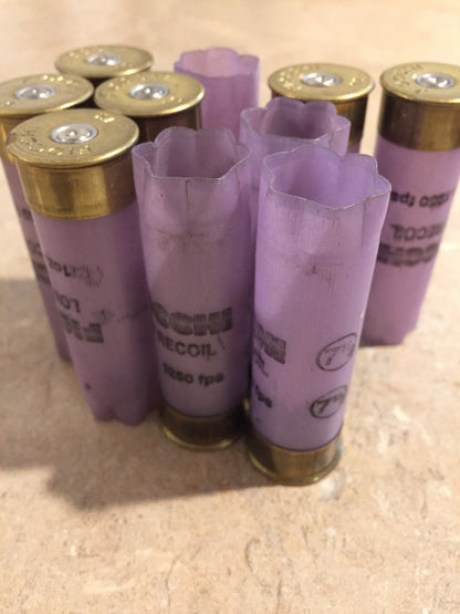Group of purple Fiocchi Low Recoil 12 gauge shotgun shells, some with crimped star-fold tops and some with brass base caps, on a tile surface