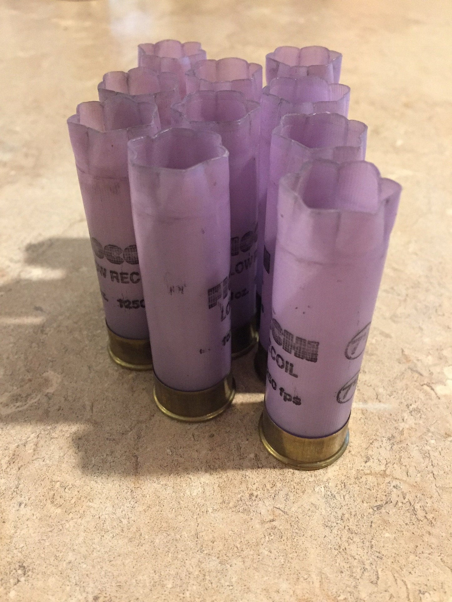 Group of purple Fiocchi 12 gauge Low Recoil shotgun shells with brass bases, standing upright on a tile surface