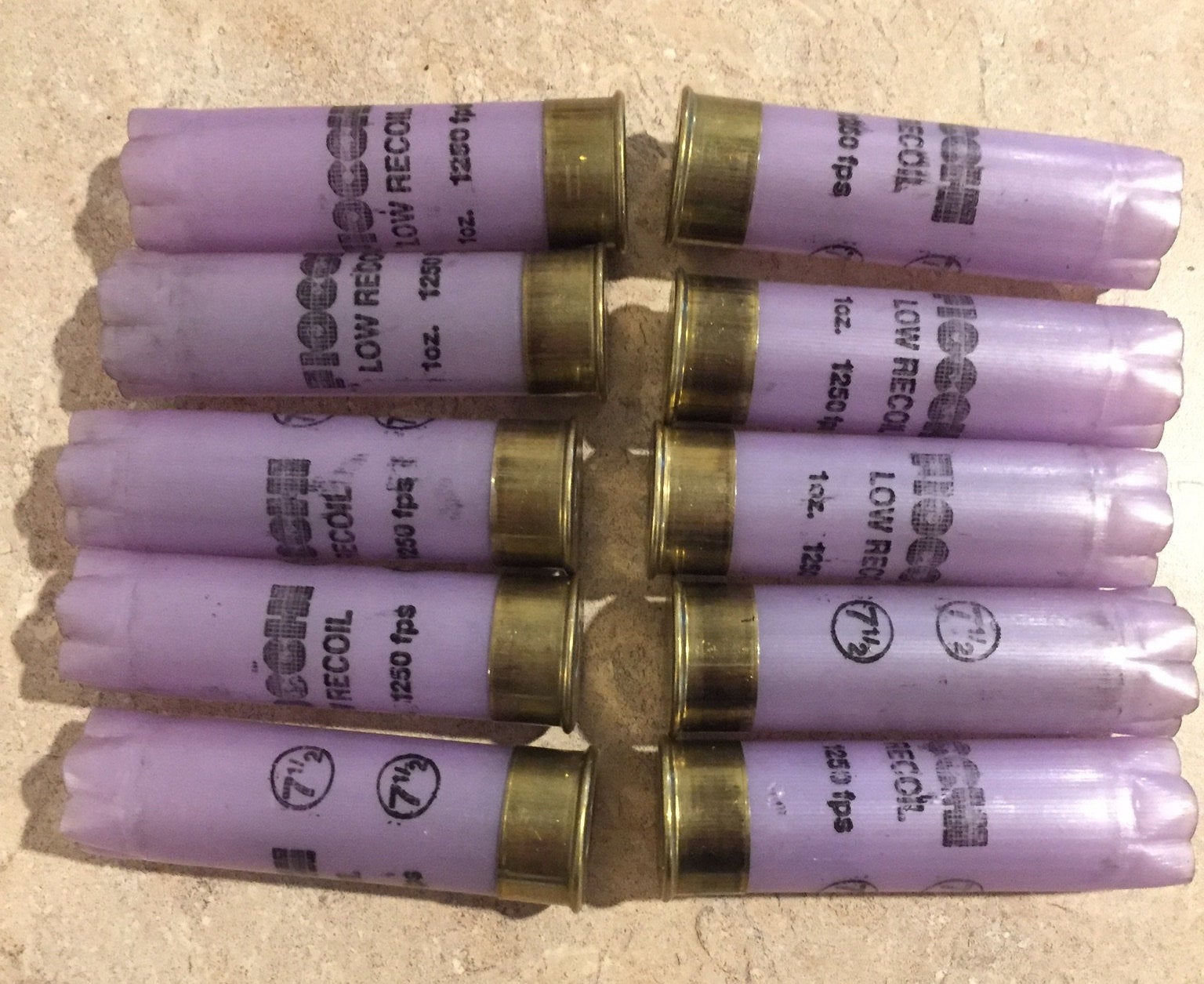 10 purple Fiocchi Low Recoil 12 gauge shotgun shells with brass bases, arranged in two rows on a tile surface