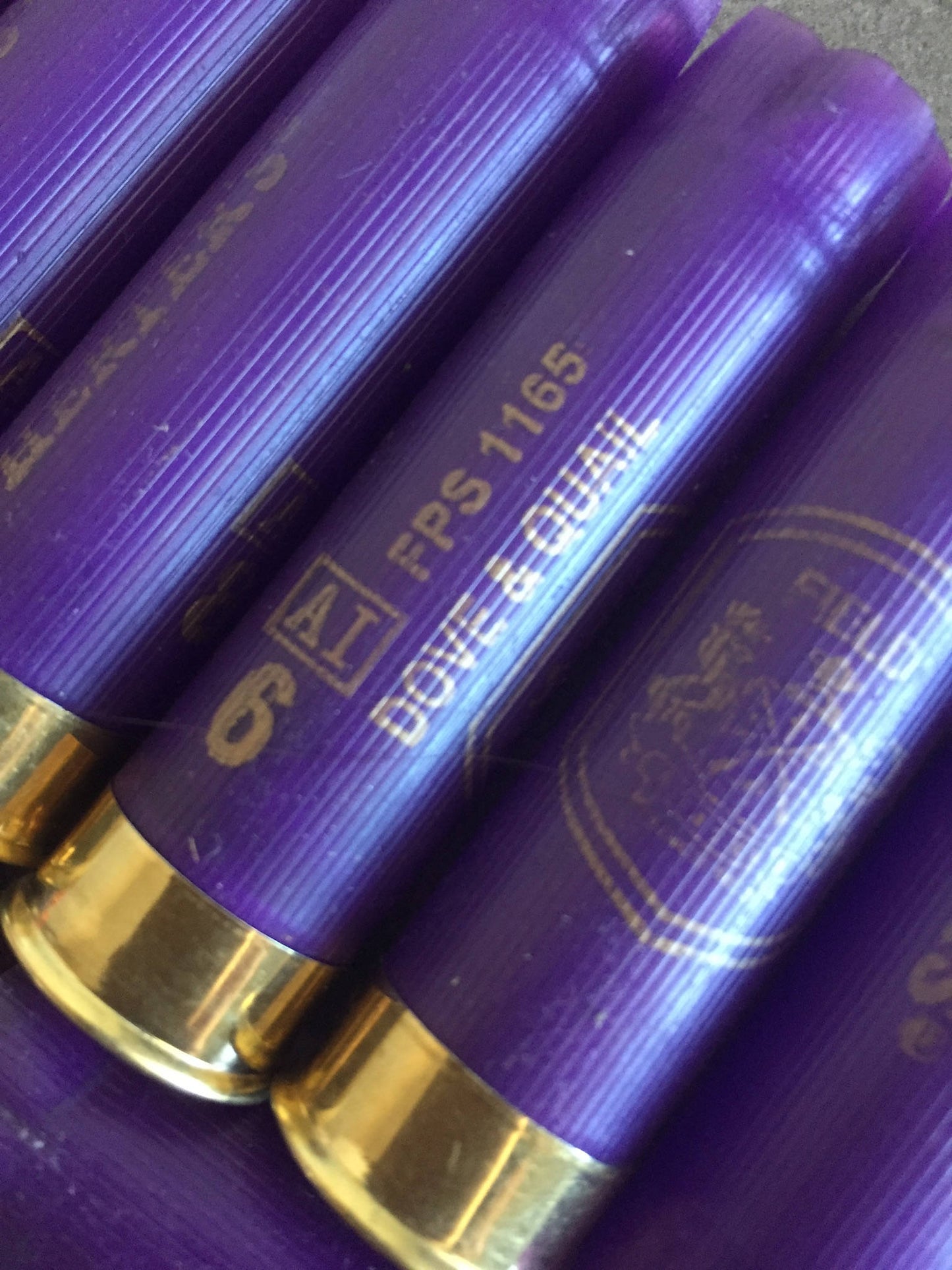 Closeup of purple 16 gauge “Dove & Quail” shotgun shells showing brass bases and printed load markings
