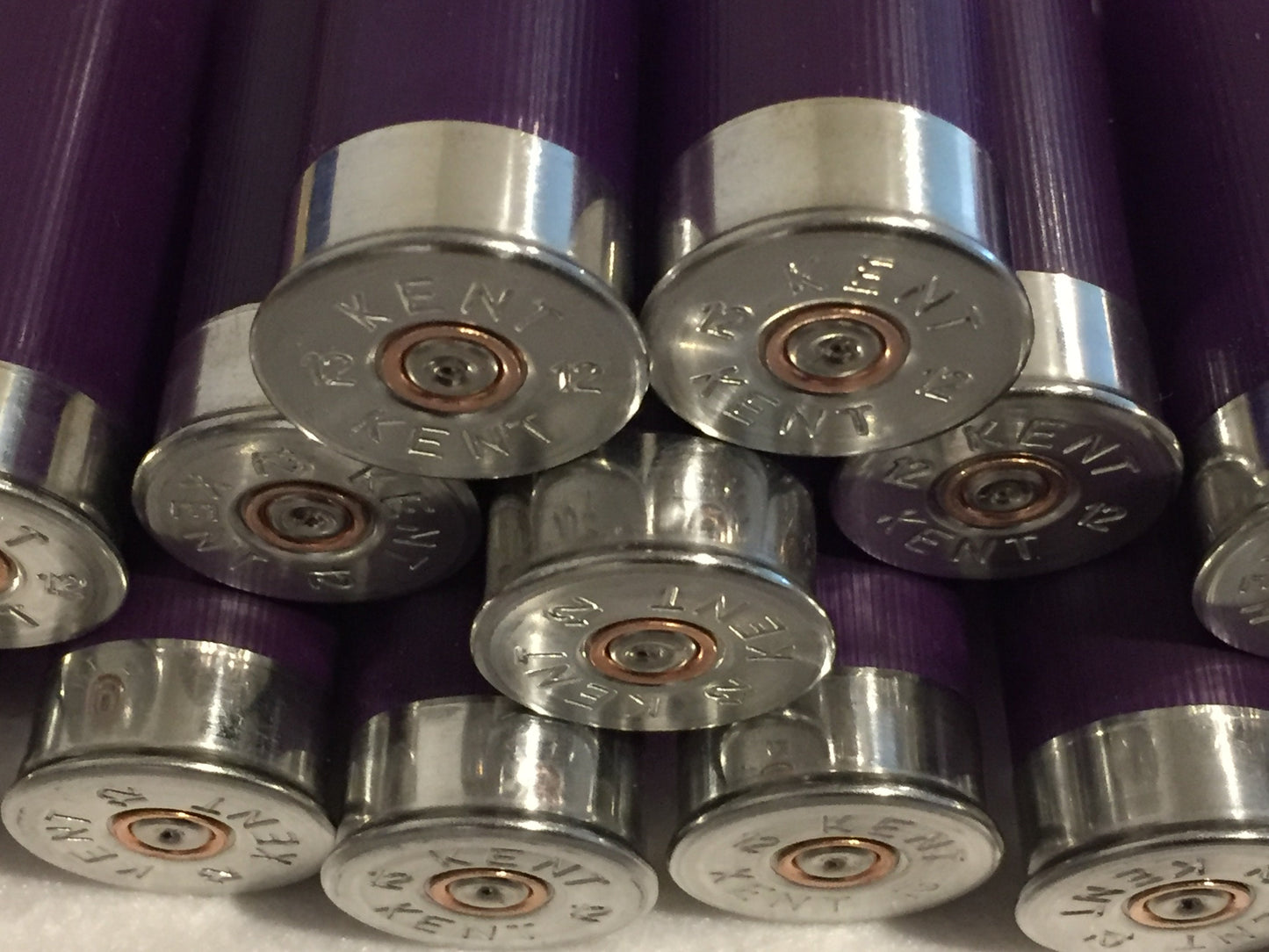 Close-up of purple shotgun shell silver bases in cluster, Kent 12 headstamps with copper primer centers