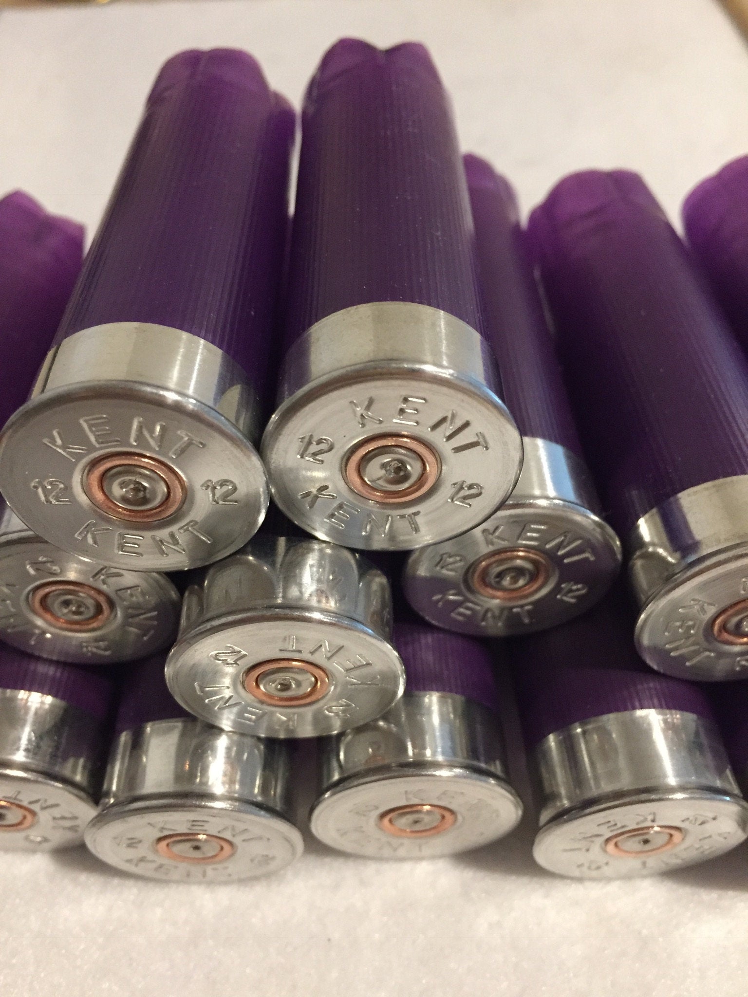 Cluster of purple shotgun shells viewed from silver base end, Kent 12 gauge headstamps with copper primers