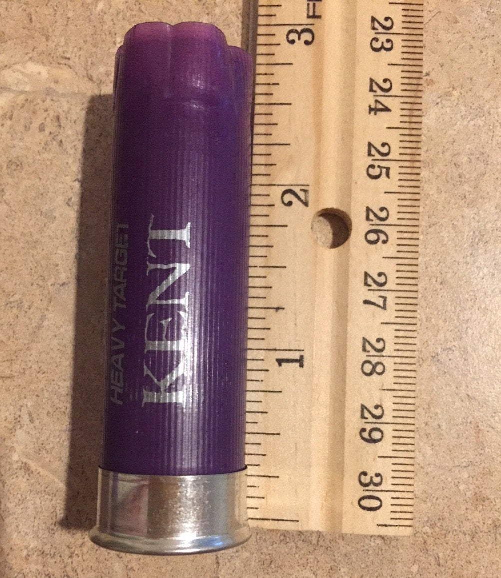 Purple Kent Heavy Target shotgun shell lying next to a wooden ruler showing its length