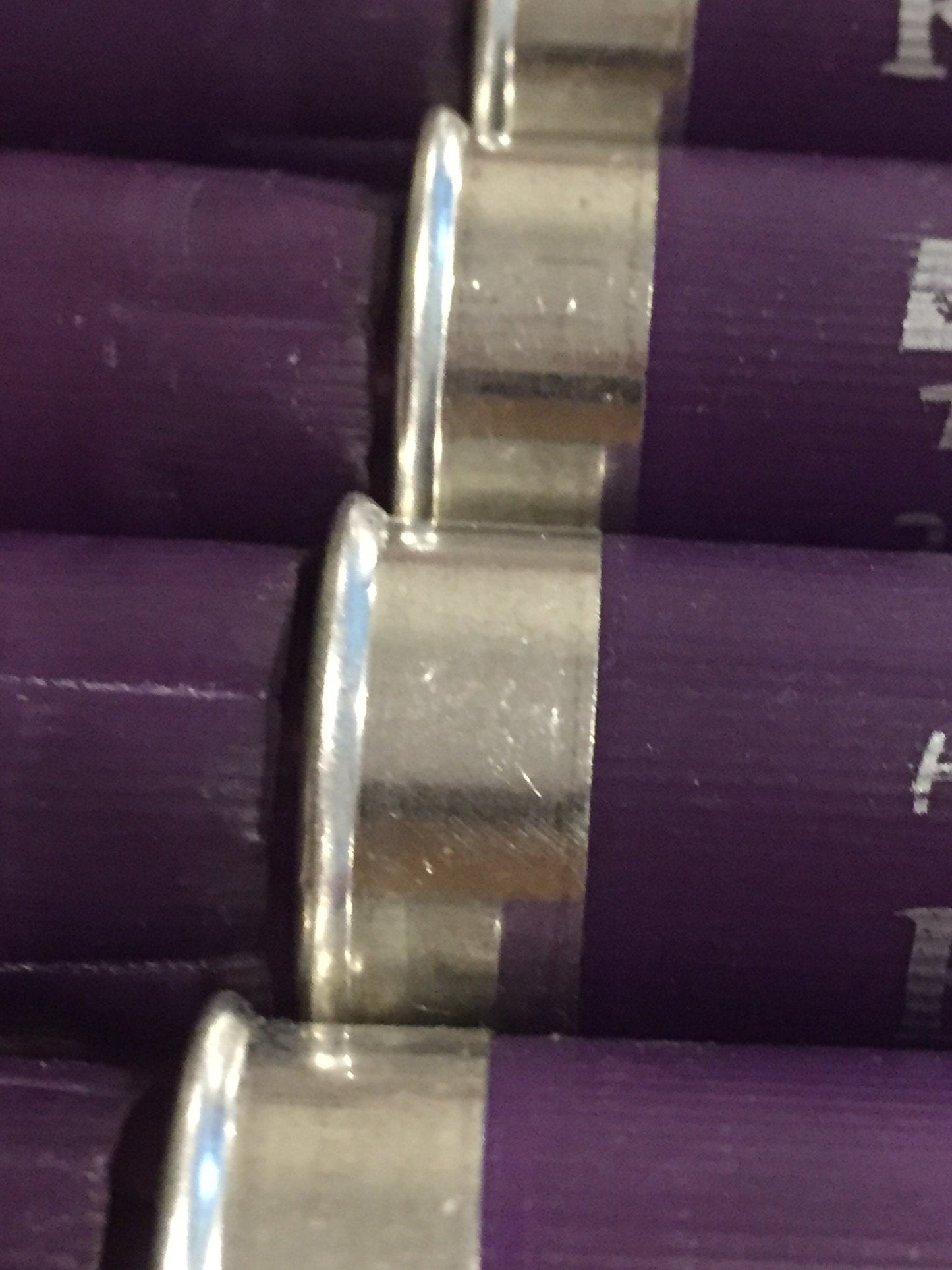 5 purple Kent Heavy Target shotgun shells lying in a row showing printed text on a stone surface