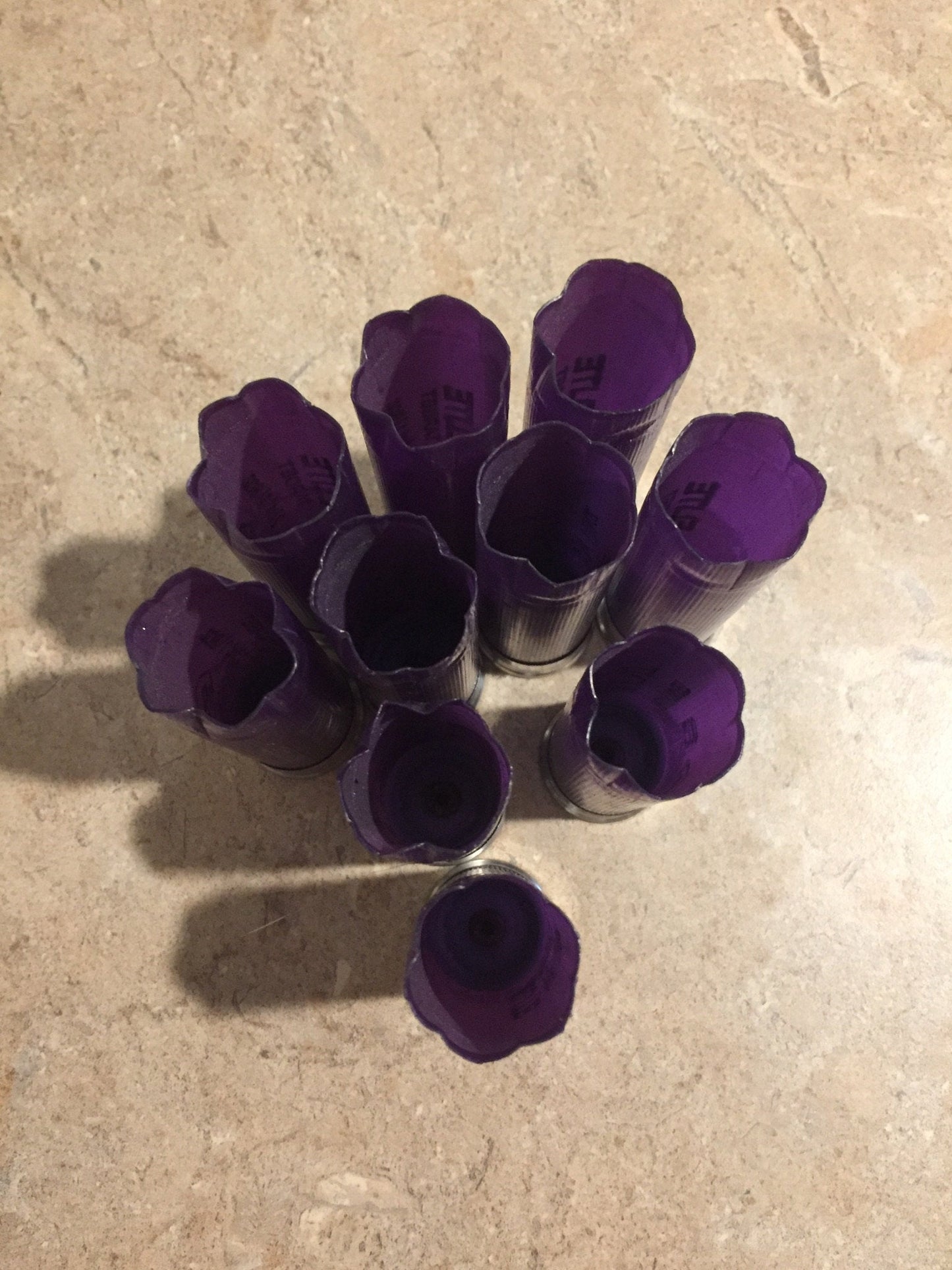 5 purple Kent Elite Target shotgun shells lying diagonally with printed text on a stone surface