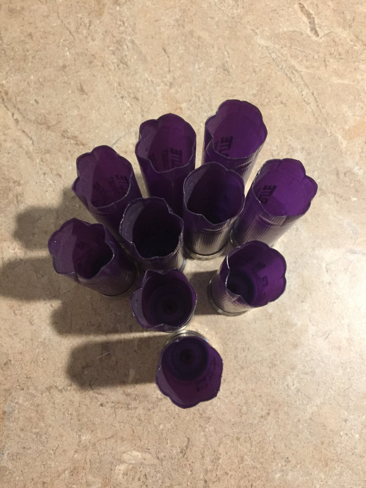 5 purple Kent Elite Target shotgun shells lying diagonally with printed text on a stone surface
