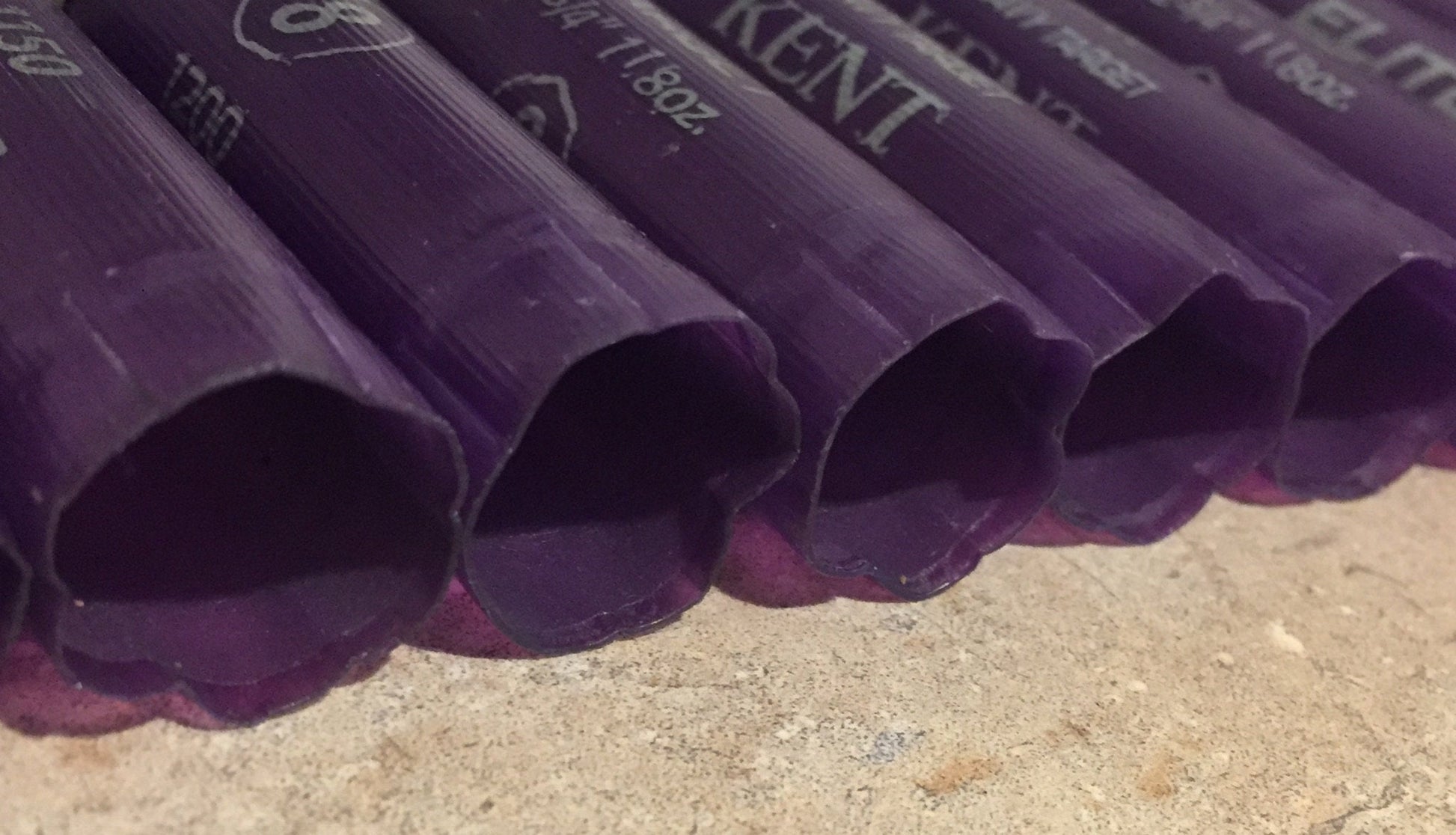 6 purple Kent shotgun shells viewed from above showing open mouths with printed text