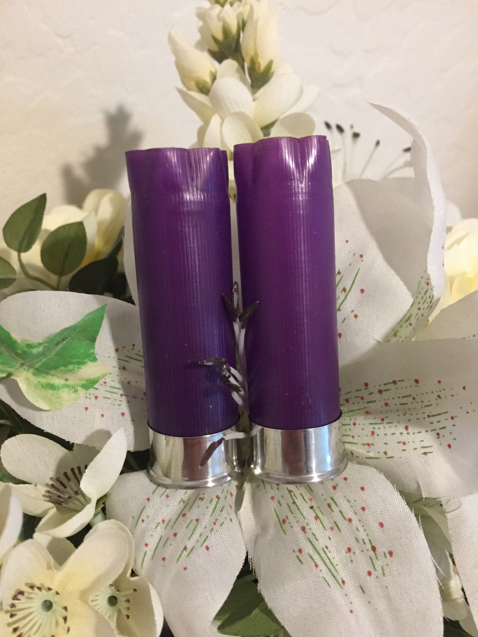Two purple empty shotgun shell hulls used in a white floral boutonniere