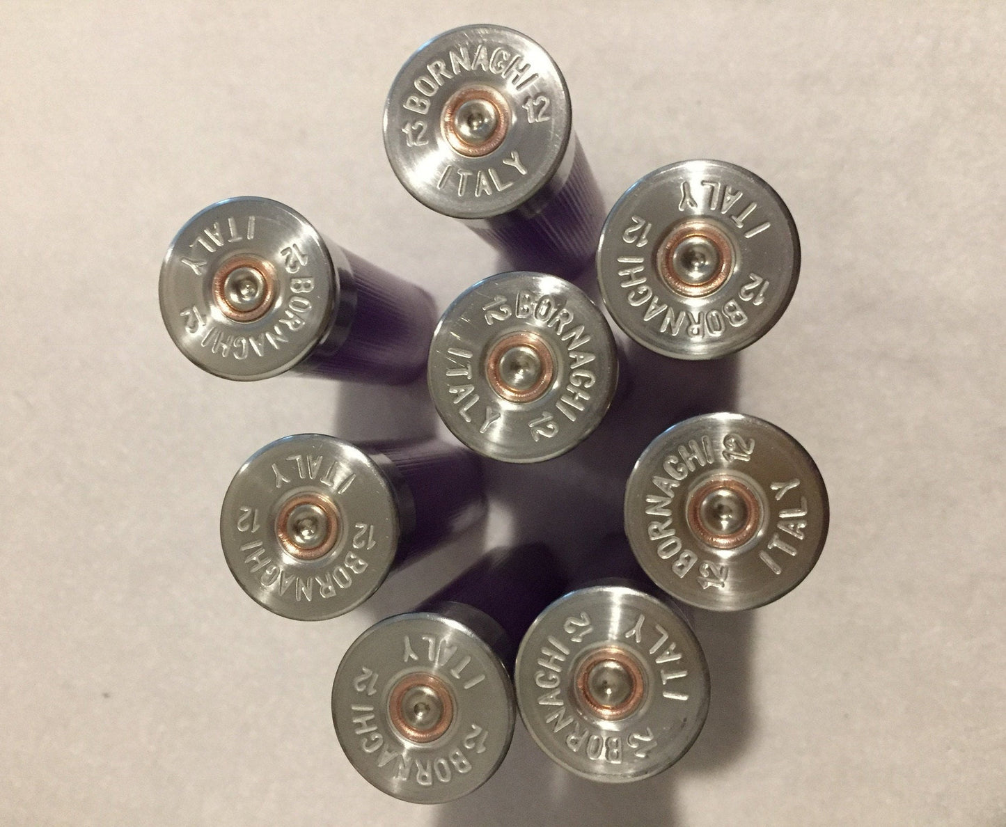 Group of silver-colored shotgun shell headstamps facing the camera