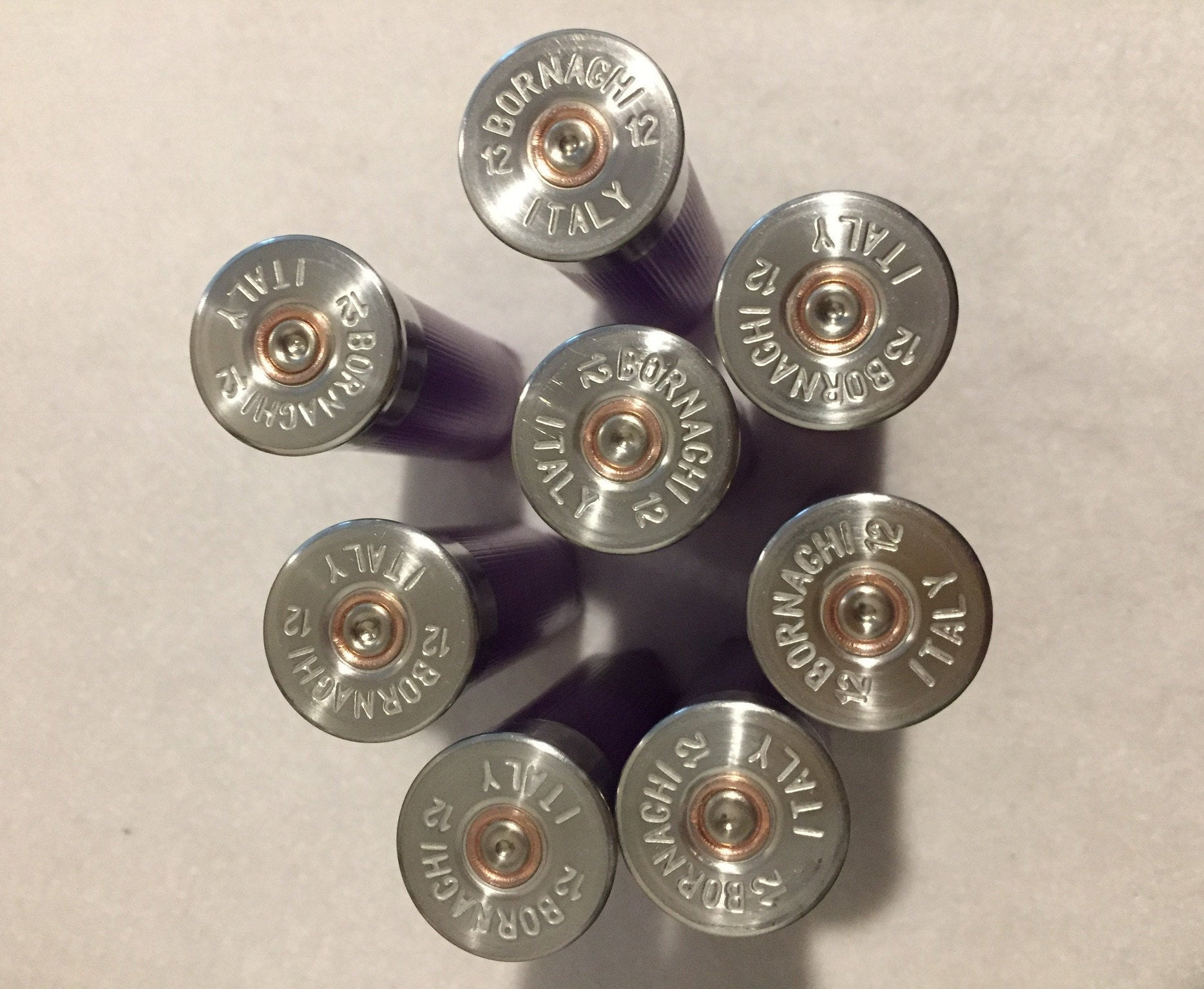 Group of silver-colored shotgun shell headstamps facing the camera