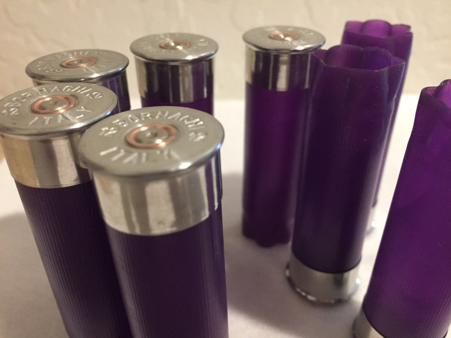 Close-up of silver-colored metal bases on purple empty 12-gauge shotgun shell hulls