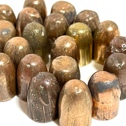 A ring of tarnished copper jacketed 45 ACP fired bullets with flattened tips standing on a white background