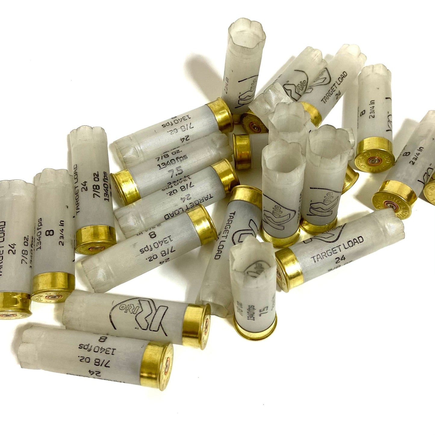 A cluster of multiple clear translucent spent 12 gauge recycled shotgun shells with gold brass bases scattered on a white background.
