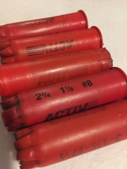 5 red plastic shotgun shells lying in a row printed "Activ", "2¾ 1⅛ #8", and "3-1⅛-#7½" text