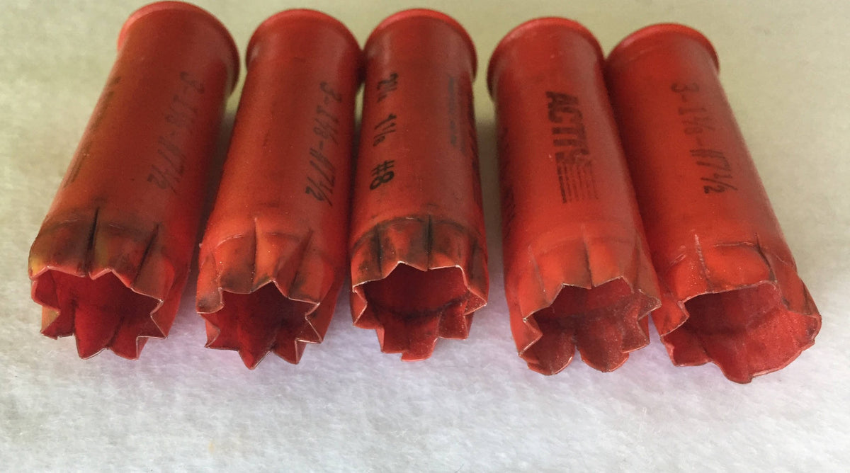 5 red plastic shotgun shells lying in a row showing open star-crimped mouths and printed "3-1⅛-#7½" text