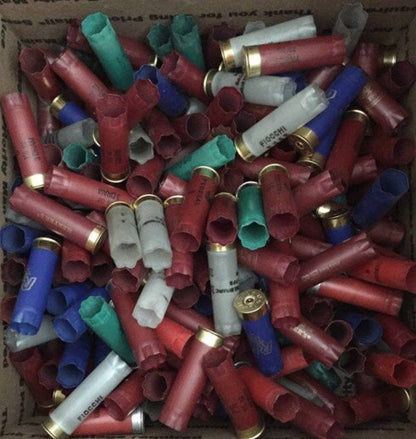 Box filled with mostly red, blue, green, and gray empty shotgun shell hulls